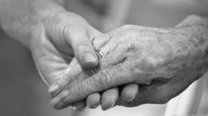 An image of a young person's hand holding an older person's hand